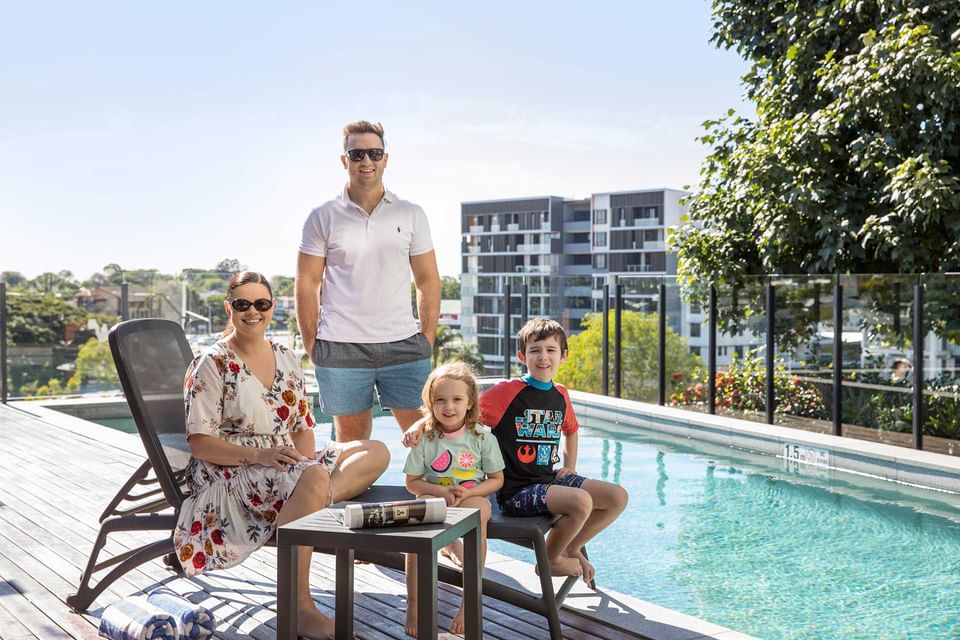 Family posing on the pool deck by the outdoor pool at Alcyone Hotel Residences