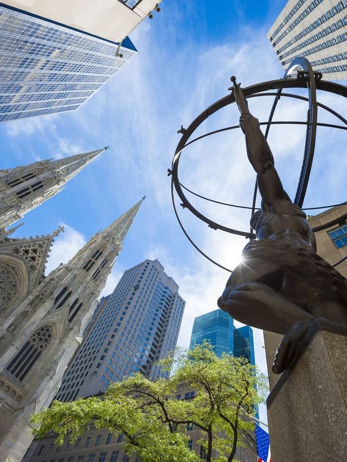 Atlas statue by St. Patrick's Cathedral under a bright sun near the city near Warwick Paris Champs Elysées