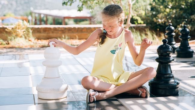 Chica sentada sobre un gran tablero de ajedrez en Live Aqua Resorts