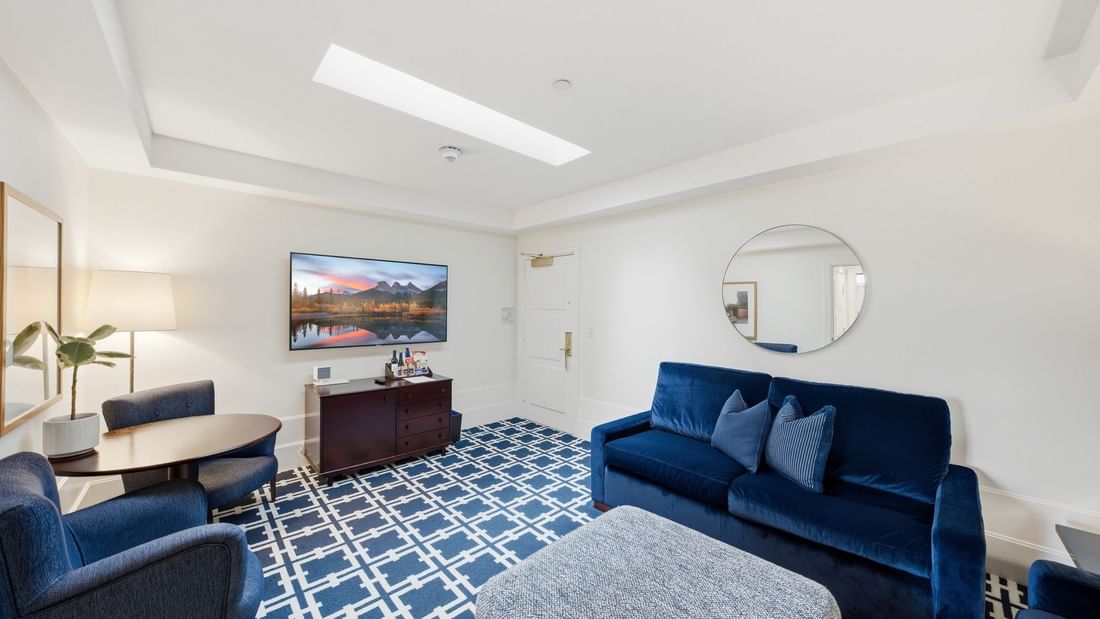 Deluxe King Suite living area with blue velvet sofa, patterned rug, and skylight at el PRADO Hotel, Palo Alto.