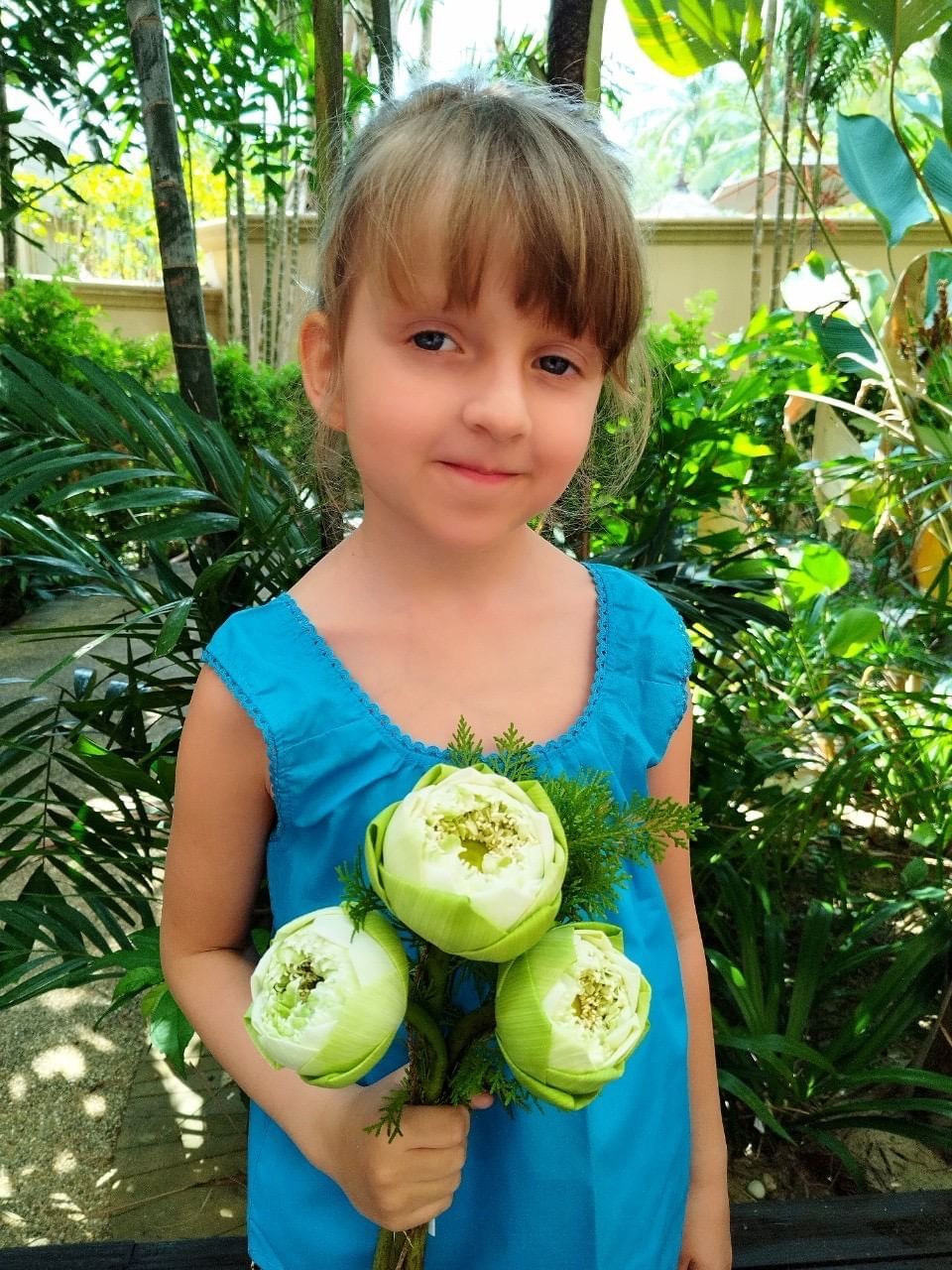 A girl wearing Thai traditional costume is holding the beautiful folding lotuses