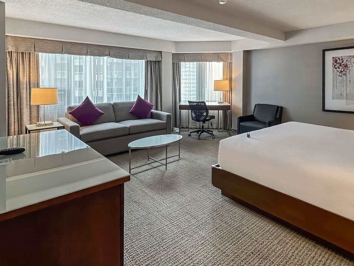 Hotel bedroom with bed, sofa bed, TV, and table