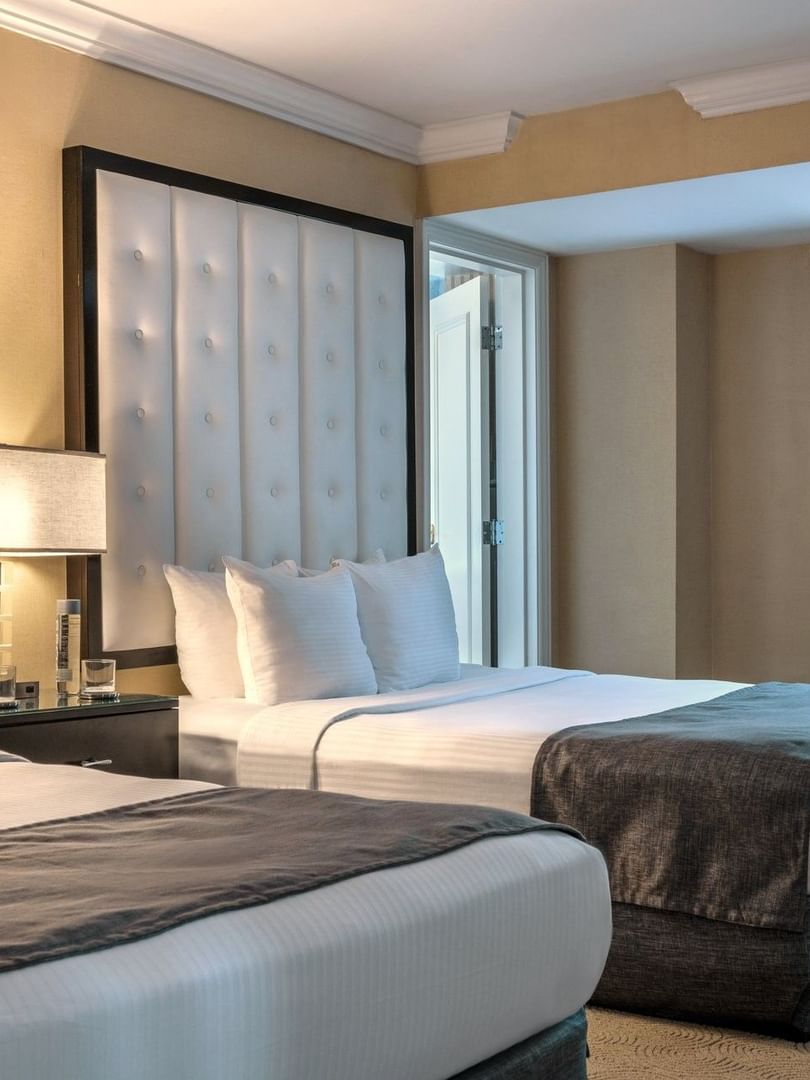 Two queen beds with white linens and brown blankets in a Premium Suite at Warwick Allerton Chicago