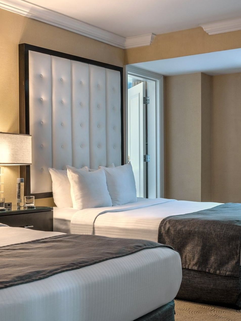 Two queen beds with white linens and brown blankets in a Premium Suite at Warwick Allerton Chicago