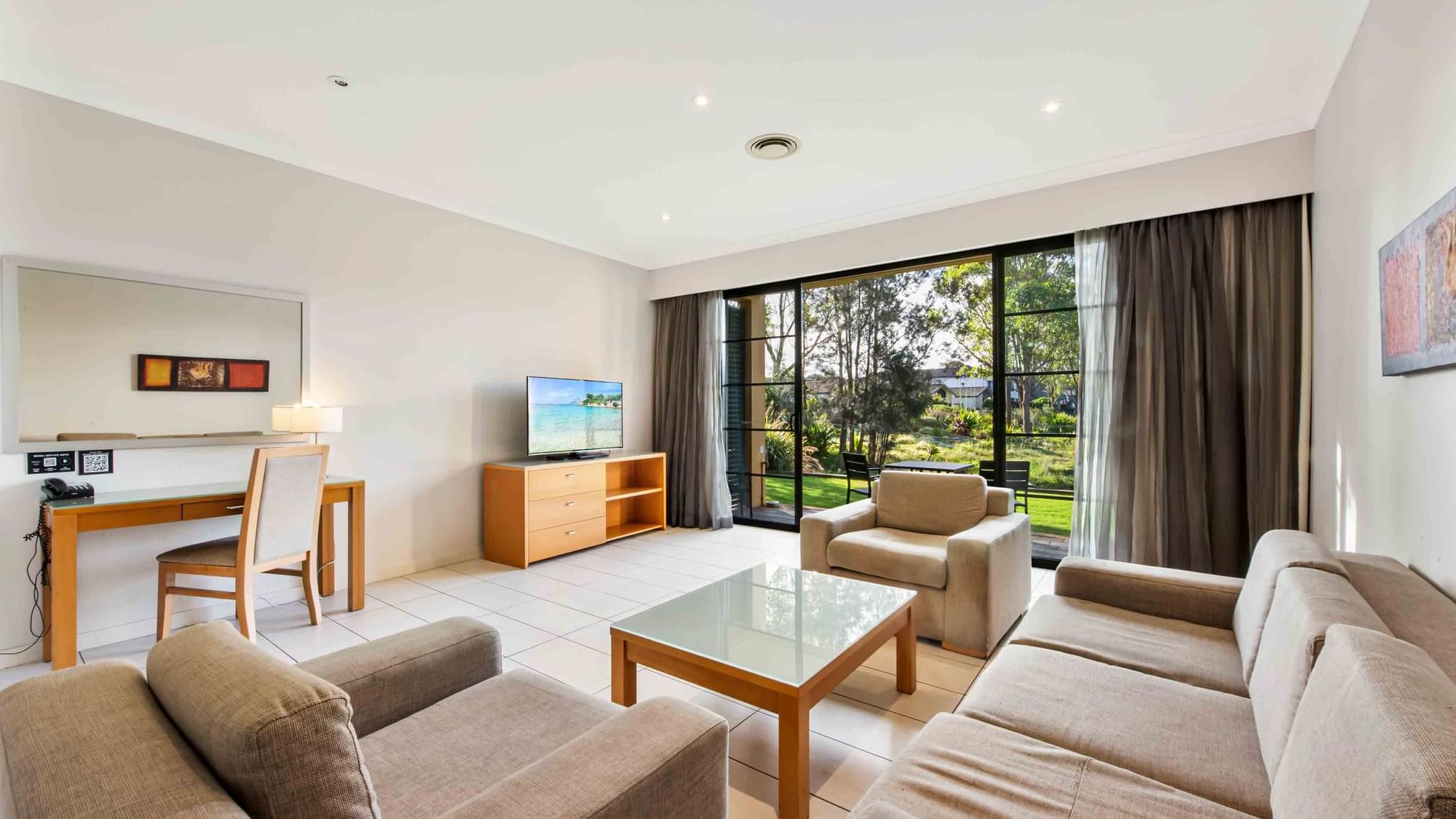 Three Bedroom Apartment living room with a lake view through large windows, sofas, and a TV at Mercure Kooindah Waters