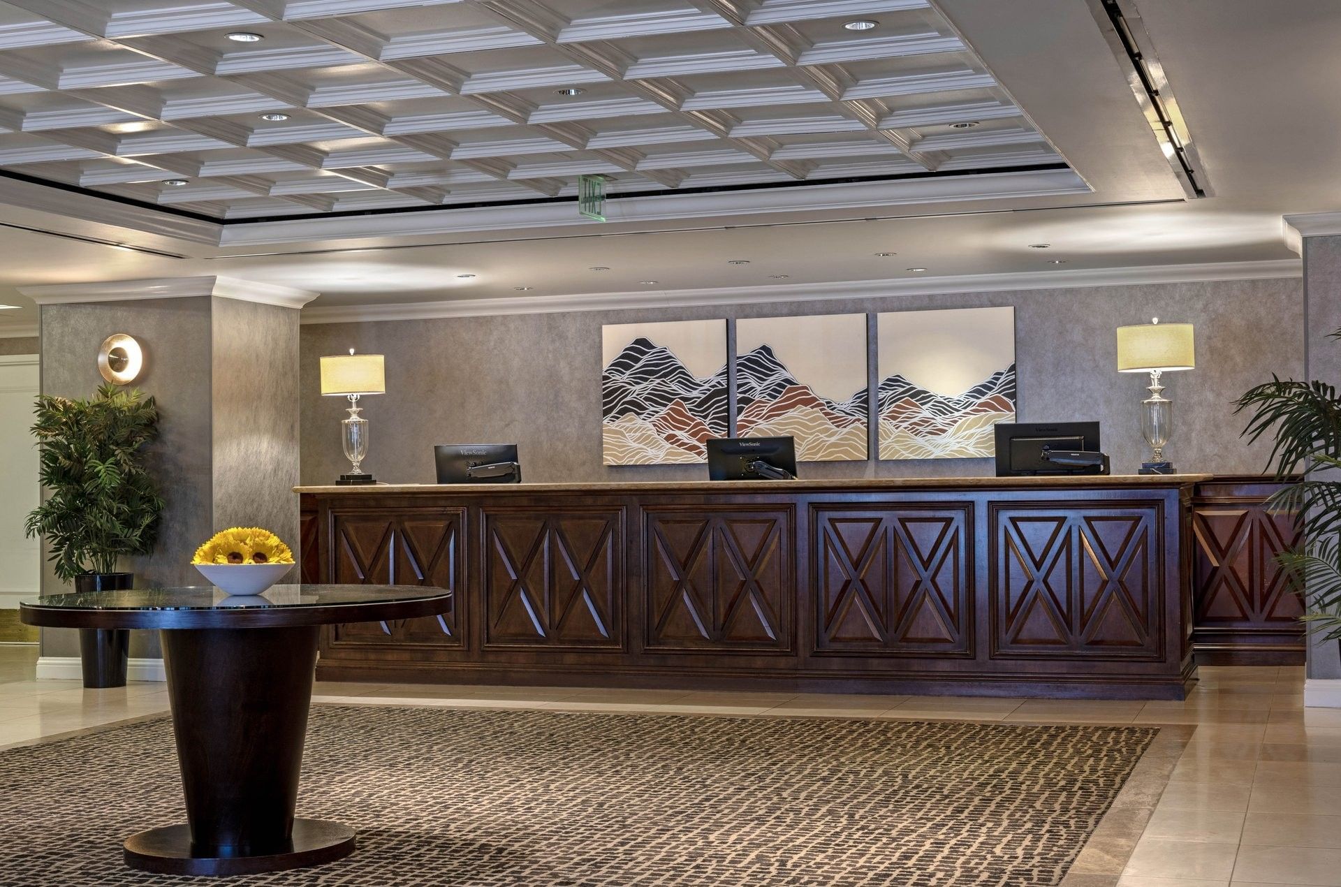 Long wood desk by lamps under a coffered ceiling near mountain art at Warwick Denver