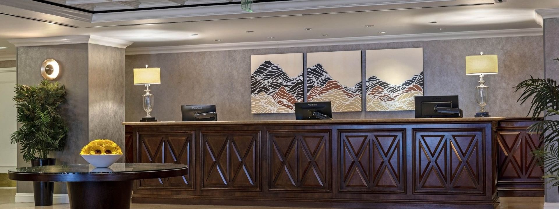 Long wood desk by lamps under a coffered ceiling near mountain art at Warwick Denver