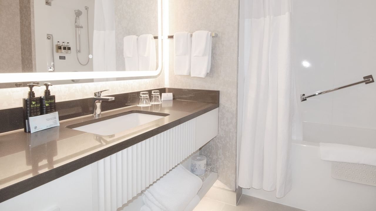 Hotel washroom with bathtub, sink, soap, towels and mirror