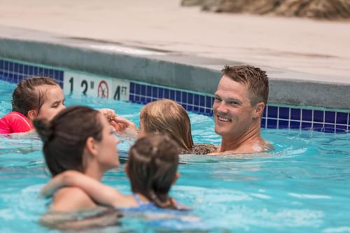 A family enjoying their stay in the outdoor swimming pool at Blackcomb Springs Suites