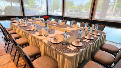 Large U-shaped meeting room with a large square table & grey chairs, and floral centerpieces in Vip Private at Hotel Mirra
