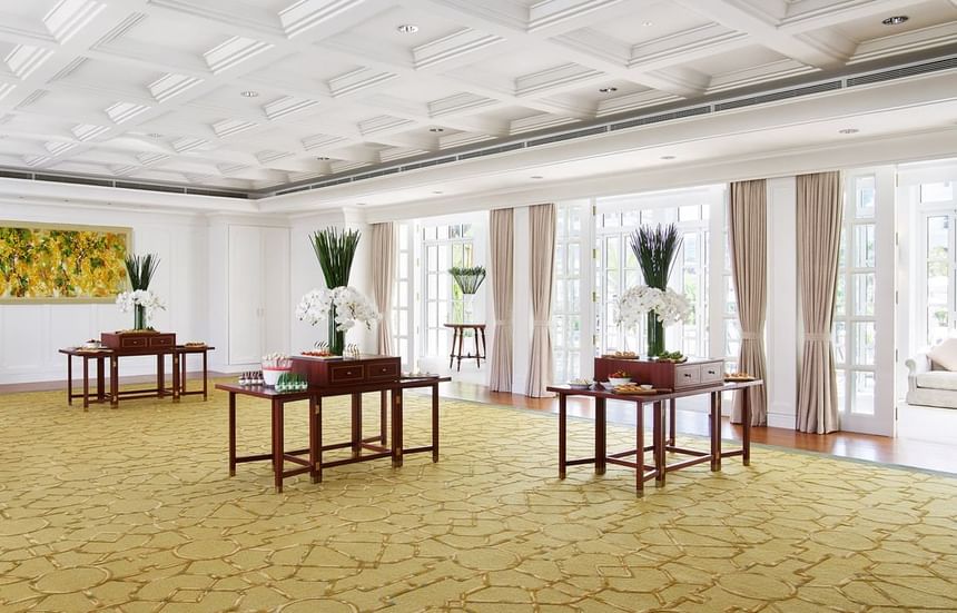 Elegant event space with floral centerpieces, wooden tables, and large windows in Pool House at Park Hyatt Saigon