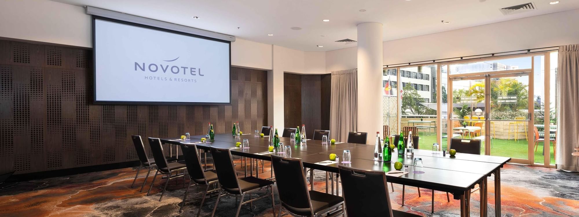 Boardroom set-up facing the projector screen in The Hunter Room 4 at Novotel Sydney on Darling Harbour