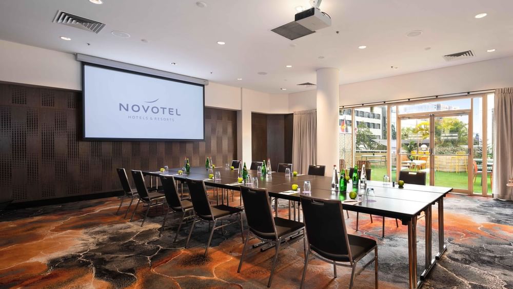 Boardroom set-up facing the projector screen in The Hunter Room 3 at Novotel Sydney on Darling Harbour