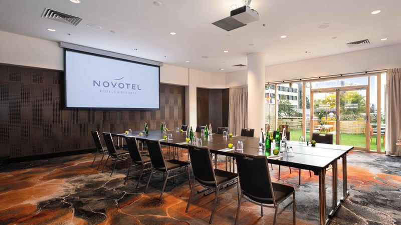 Boardroom set-up facing the projector screen in The Hunter Room 3-4 at Novotel Sydney on Darling Harbour