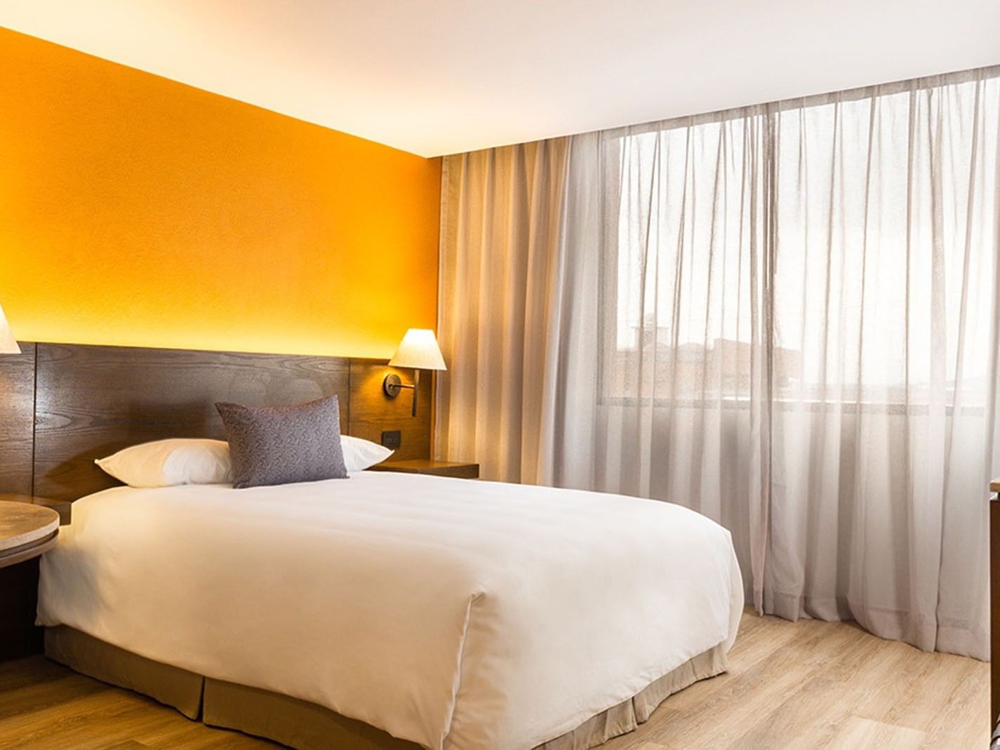 Queen Deluxe Superior room featuring a single bed with white linens by an orange wall at Camino Real Aeropuerto Mexico
