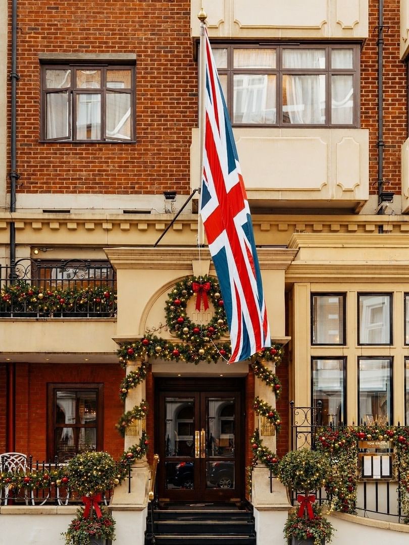 Festive hotel entrance adorned with garland, wreaths, and Union Jack flag for A Magical Christmas at The Capital Hotel.