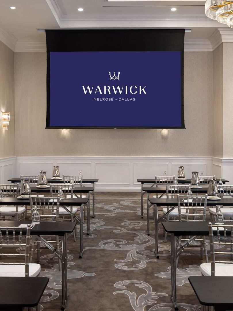 Classroom seating by a screen under a chandelier in Turtle Creek Ballroom A at Warwick Melrose Dallas