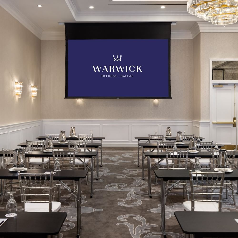 Classroom seating by a screen under a chandelier in Turtle Creek Ballroom A at Warwick Melrose Dallas