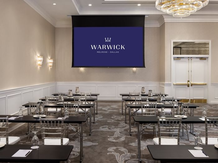 Classroom seating by a screen under a chandelier in Turtle Creek Ballroom A at Warwick Melrose Dallas