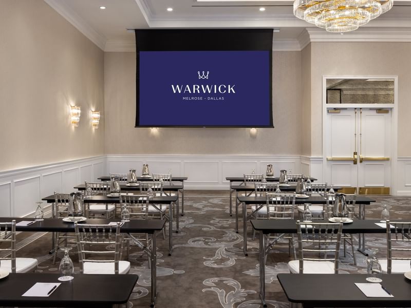 Classroom seating by a screen under a chandelier in Turtle Creek Ballroom A at Warwick Melrose Dallas