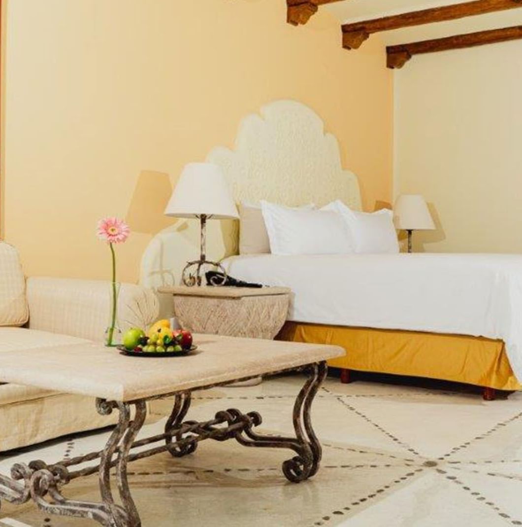 King Master Suite featuring a cream sofa by a stone table under wood beams at Quinta Real Huatulco