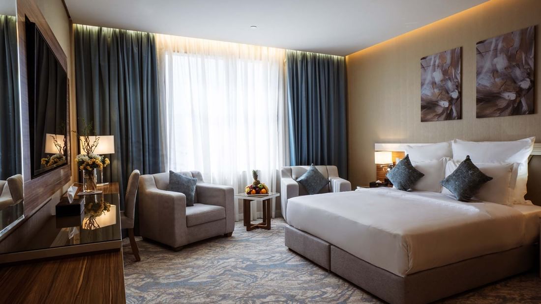 Cozy bed with TV and seating area in the Standard Room at Cantonal Hotel by Warwick Riyadh