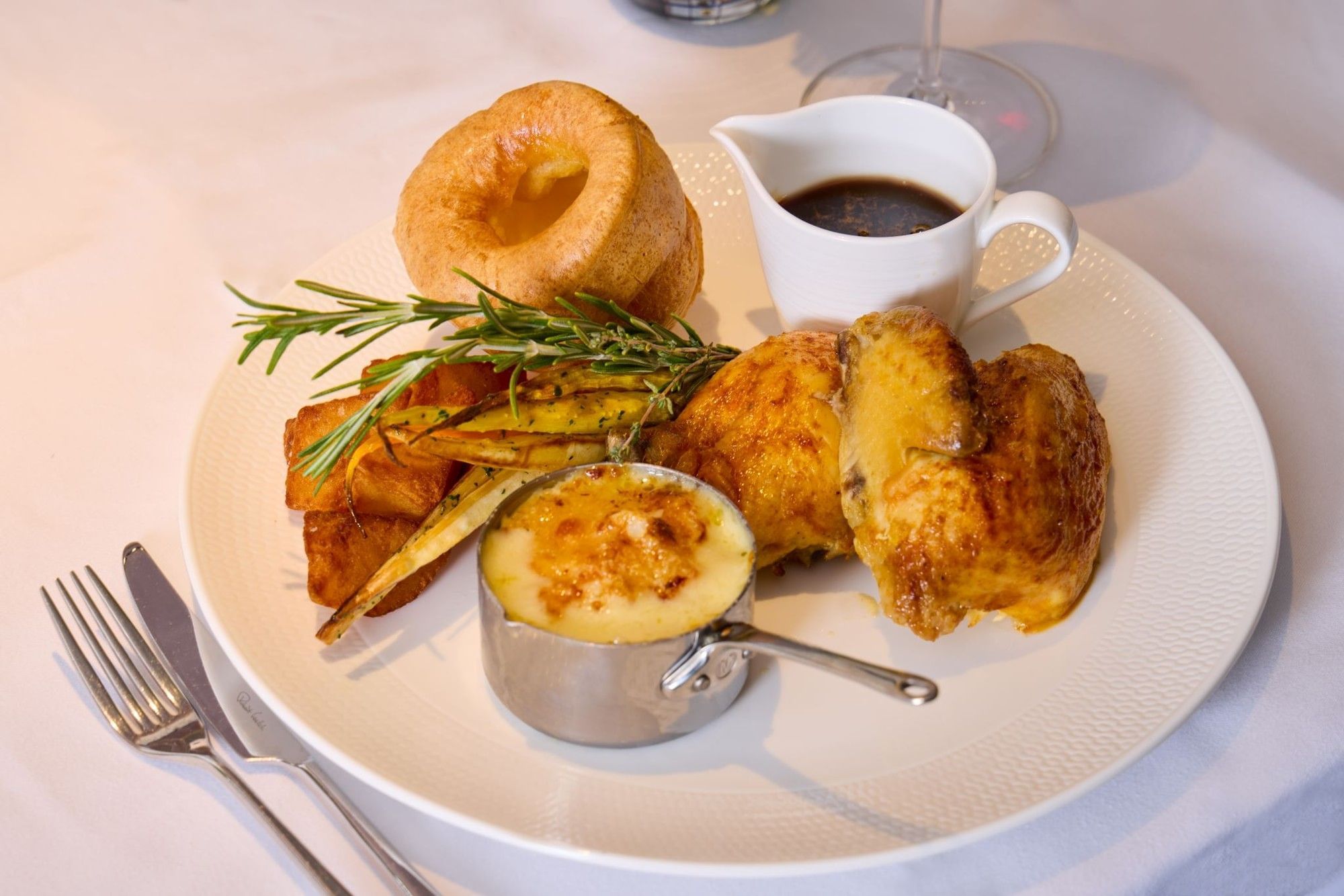Whitcomb's Sunday Roast at The Londoner Hotel, featuring roasted chicken, a Yorkshire pudding, and gravy