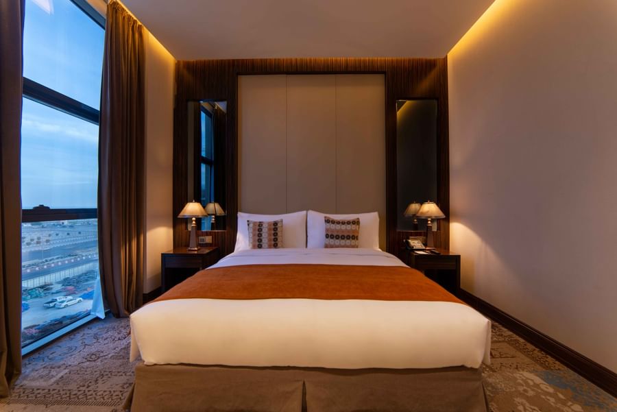 Ambassador Suite features Double bed with an orange runner by lamps under a large window at Warwick Al Khobar