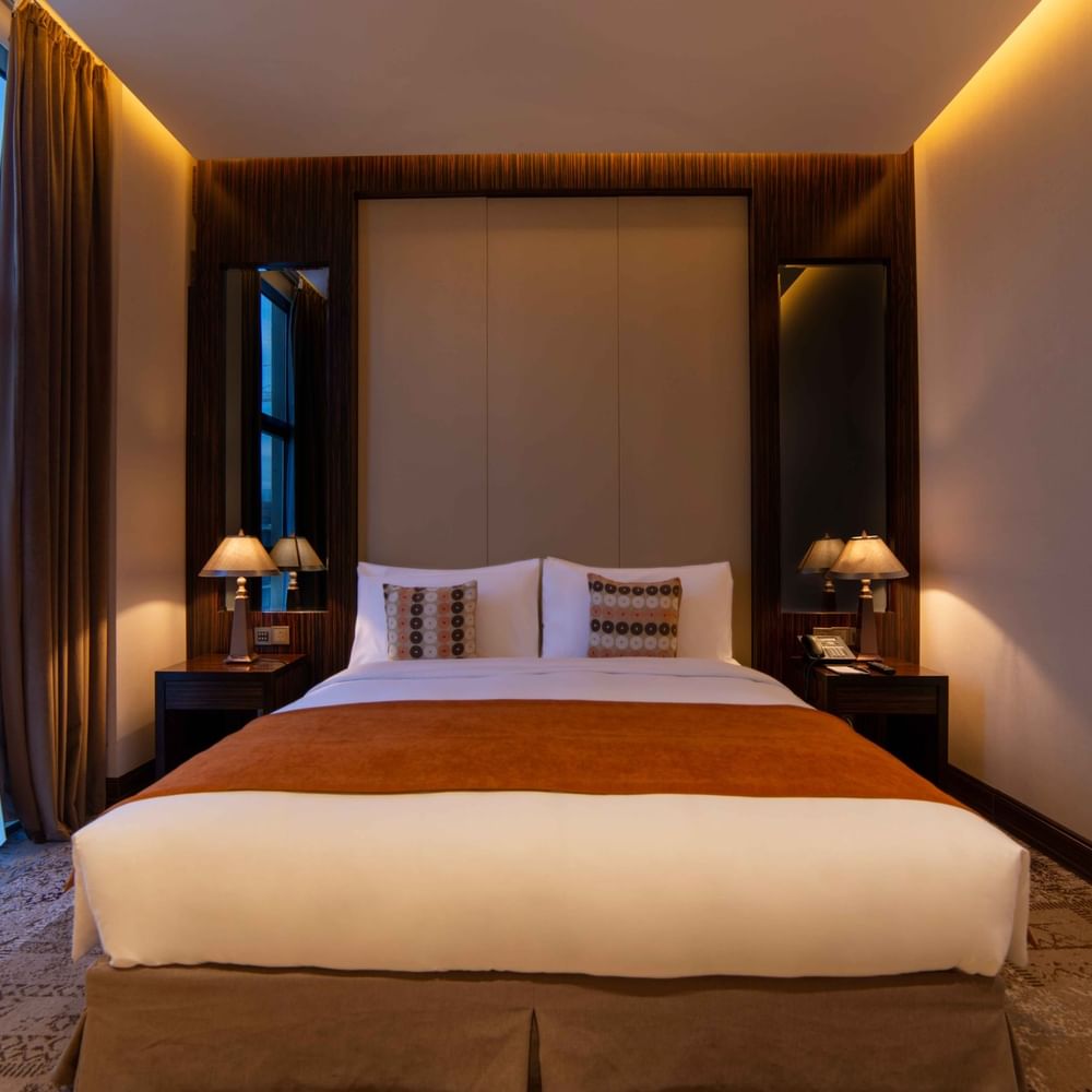 Ambassador Suite features Double bed with an orange runner by lamps under a large window at Warwick Al Khobar