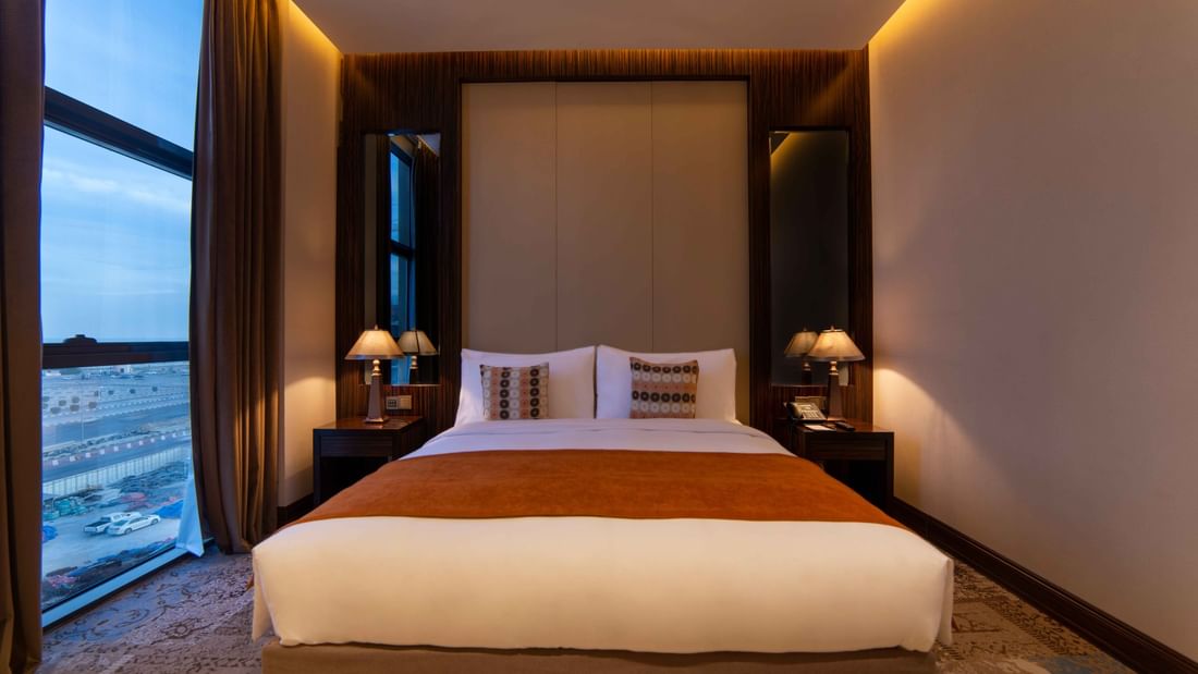 Ambassador Suite features Double bed with an orange runner by lamps under a large window at Warwick Al Khobar