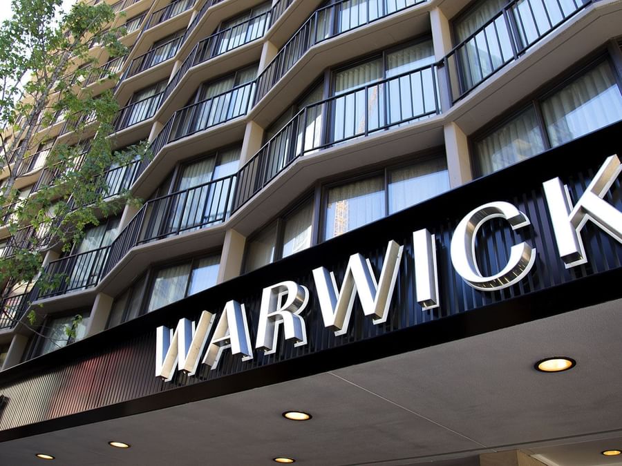 The Warwick Seattle hotel entrance features a large black sign under the balcony