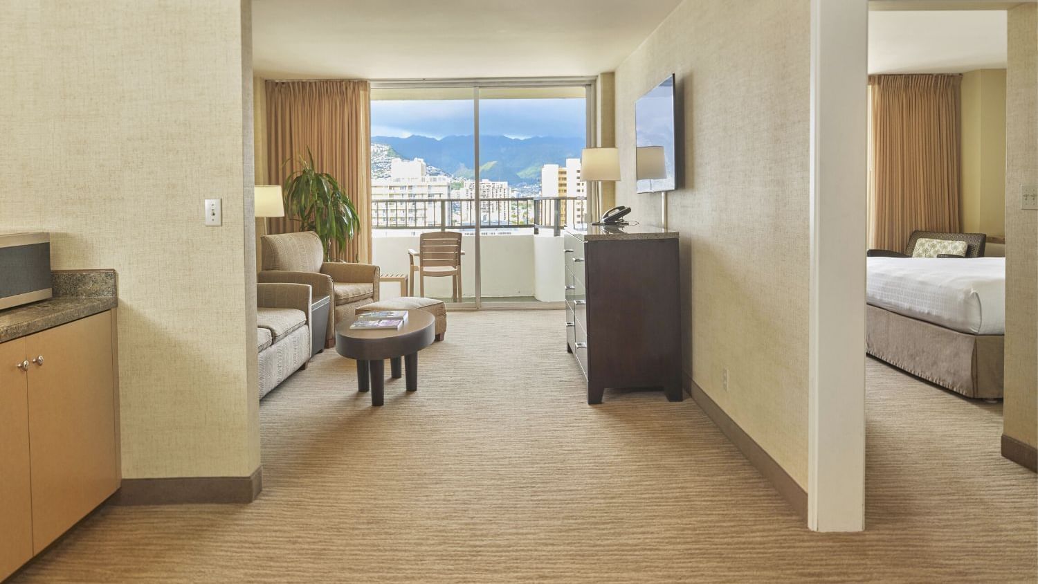 A wide view of a hotel suite with a balcony, living area, and bedroom.