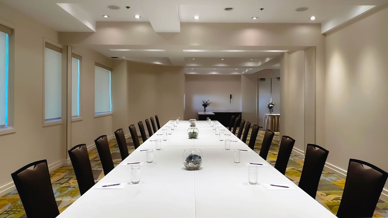 Long boardroom table set with water, pens and chairs