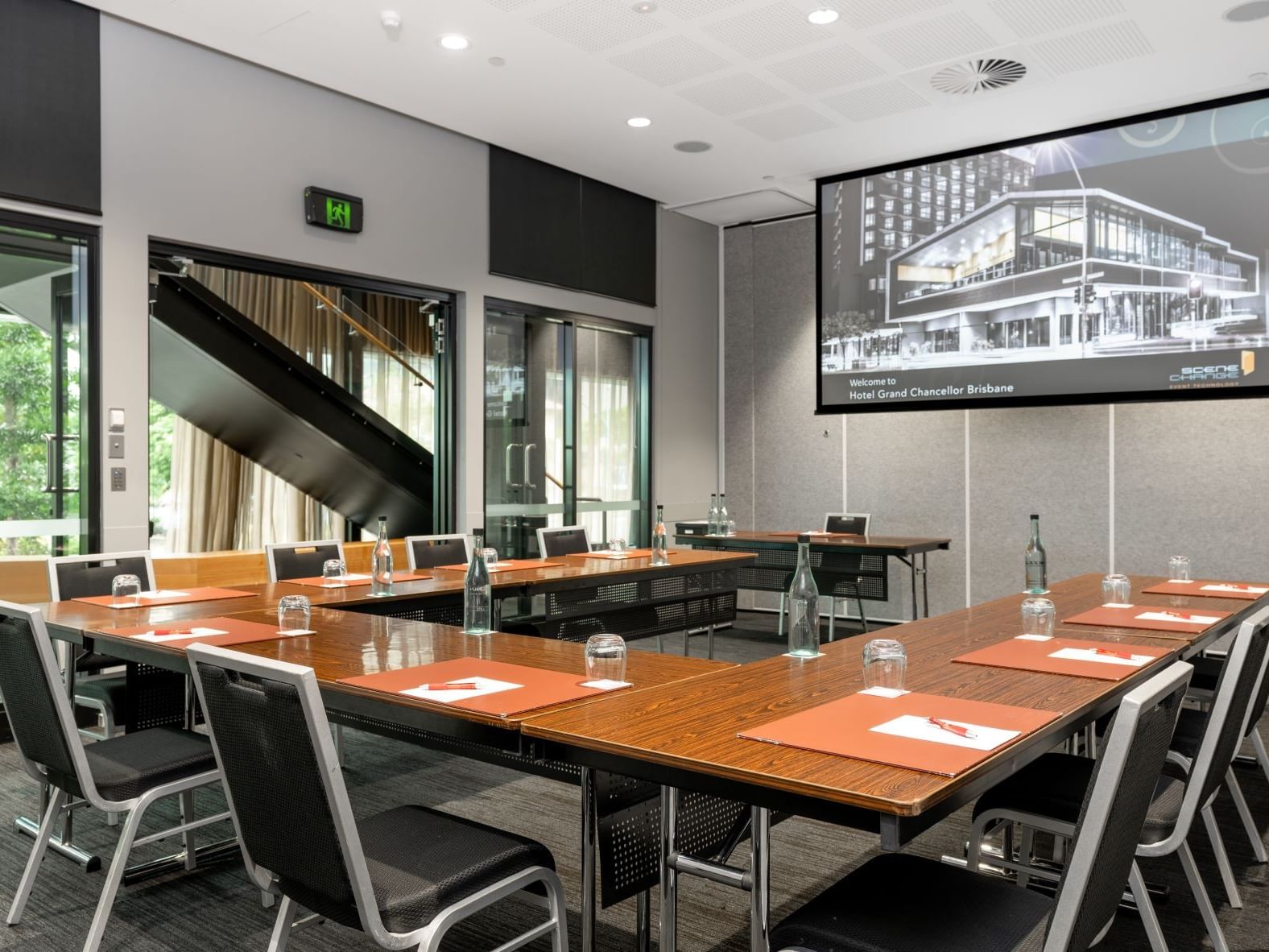 Professional conference meeting room in Brisbane with U-shape boardroom setup, projector screen, and modern event facilities at Hotel Grand Chancellor Brisbane.