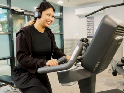 Resident on bike with headphones at Student Living - 800 Swanston gym.
