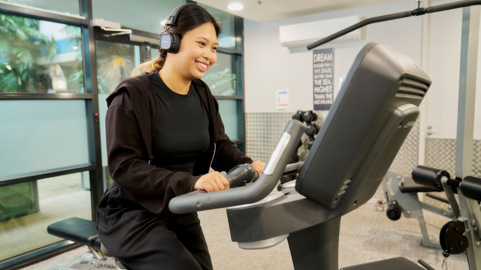 Resident on bike with headphones at Student Living - 800 Swanston gym.