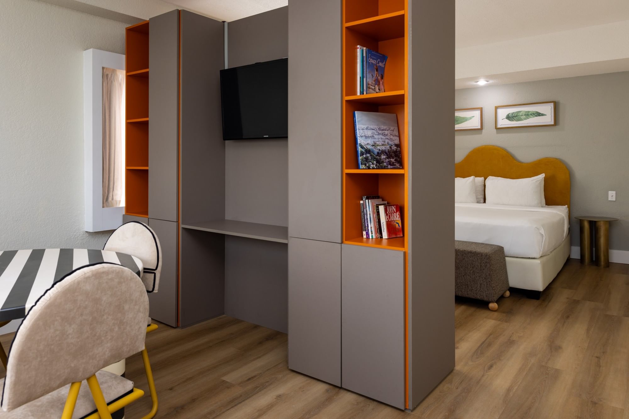 A wide view of a studio room with a desk, bookshelf, bed, and TV