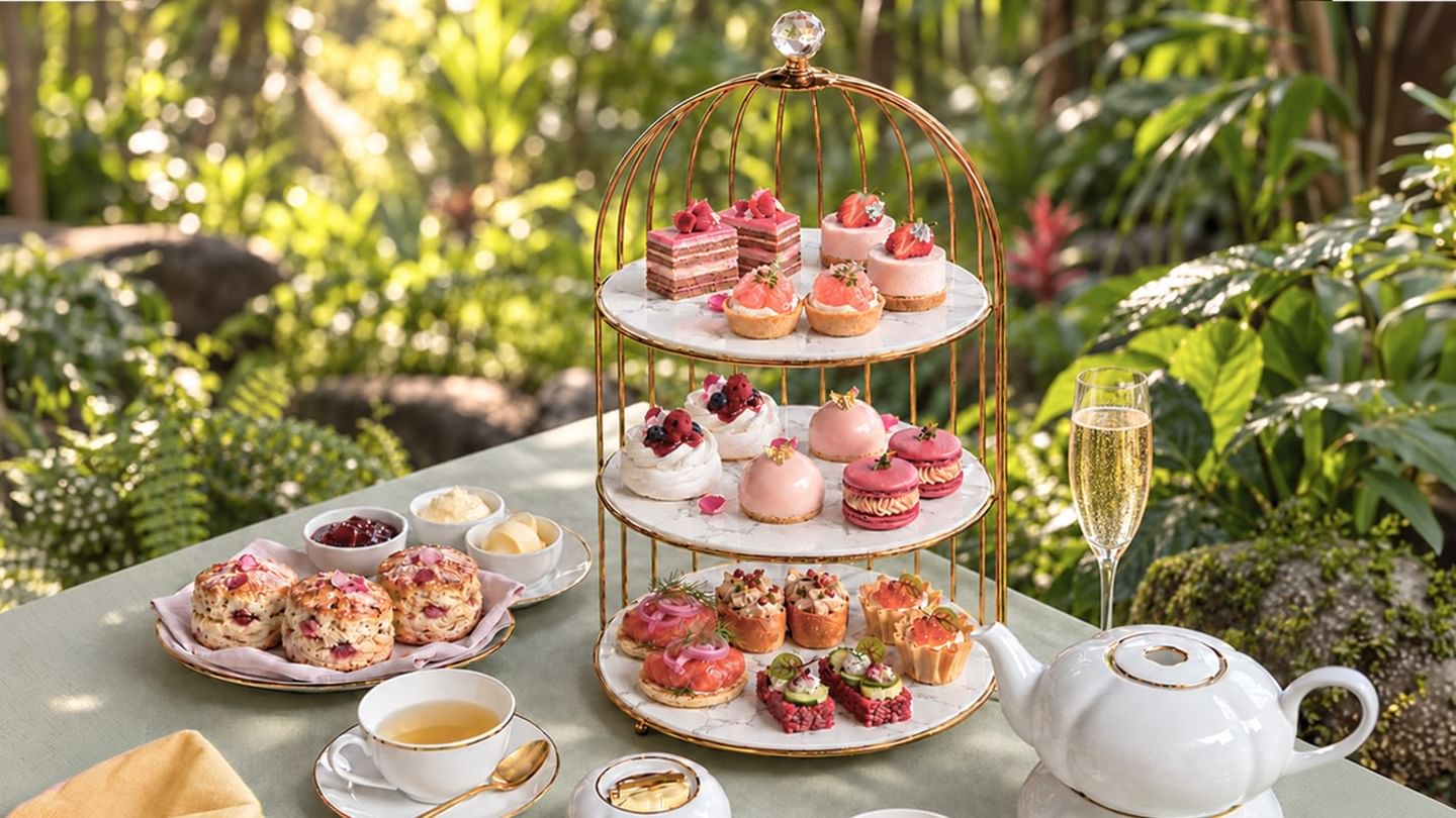 Elegant three-tier stand with pink pastries, scones, and tea service displayed on an outdoor table surrounded by lush greenery at The Banjaran Hotsprings Retreat celebrating Pink October