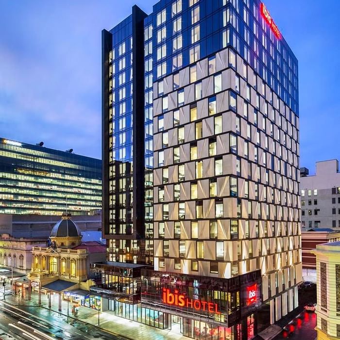 Exterior view of the Ibis Adelaide with glass facade and prominent illuminated signage