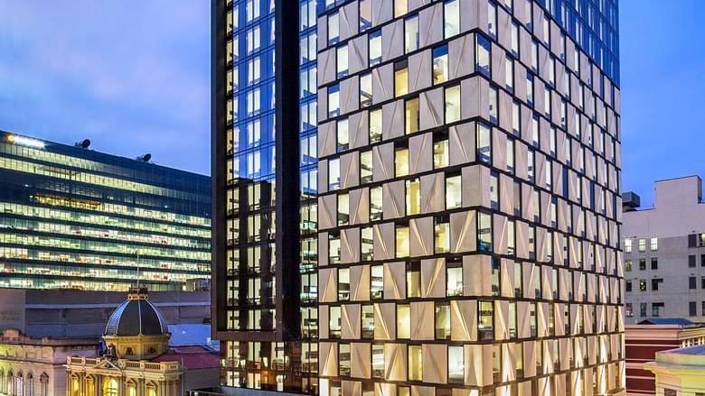 Exterior view of the Ibis Adelaide with glass facade and prominent illuminated signage