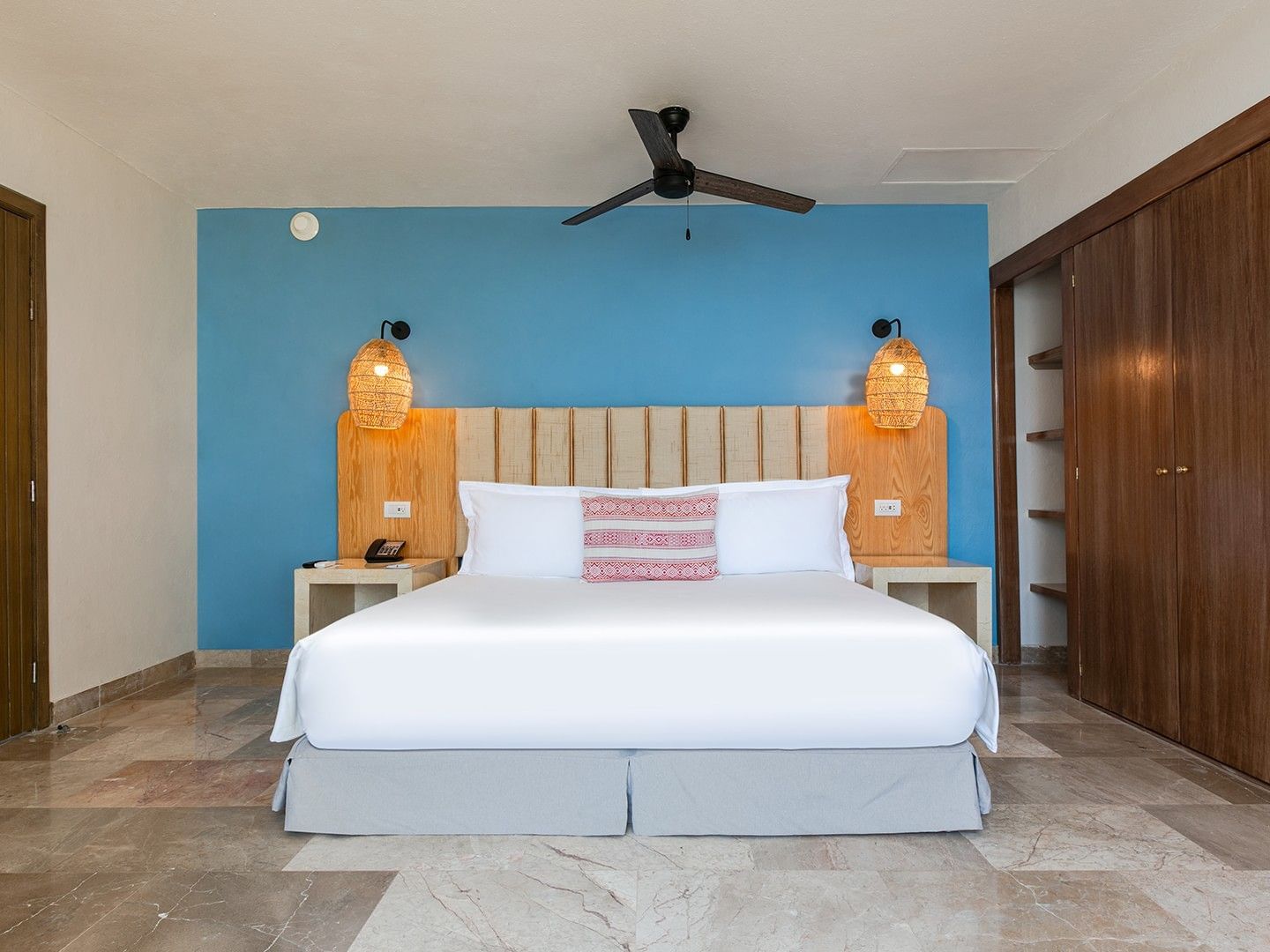 King Junior Suite with blue feature wall, wooden closet, and marble tile floor at Camino Real Acapulco Diamante
