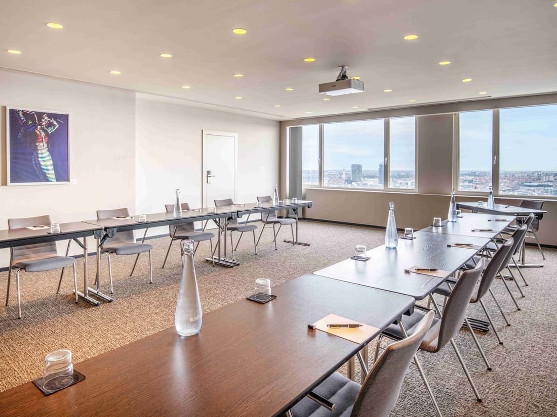 Meet 26 One conference room with a large table, chairs, and a city view from the windows at The Hotel Brussels