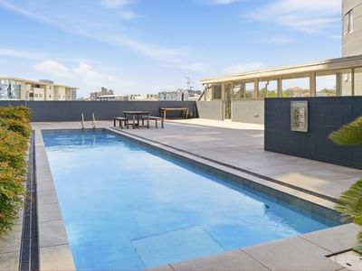 Clear pool with table and benches in a rooftop garden area at Student Living Auckland Anzac.
