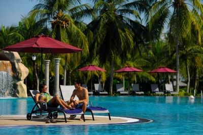 A couple on two pool chairs by the pool