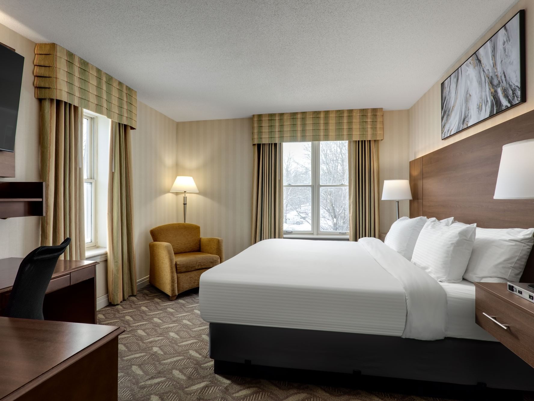 TV with work desk facing bed with couch by window in 1 Queen Bed Executive Wing Mobility Accessible at Spencer Hotel
