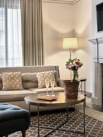 Champagne glasses on a round table near a marble fireplace at in Balcony Suite Warwick San Francisco