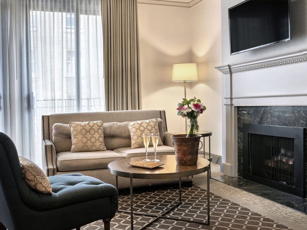 Champagne glasses on a round table near a marble fireplace at in Balcony Suite Warwick San Francisco