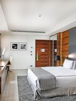 King bed by a long wooden desk under framed photos near grey curtains in Executive Room at Warwick Stone 55 - Beirut
