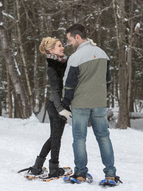 Couple holding hands while gazing at each other in the snowy forest near Cove Pocono Resorts