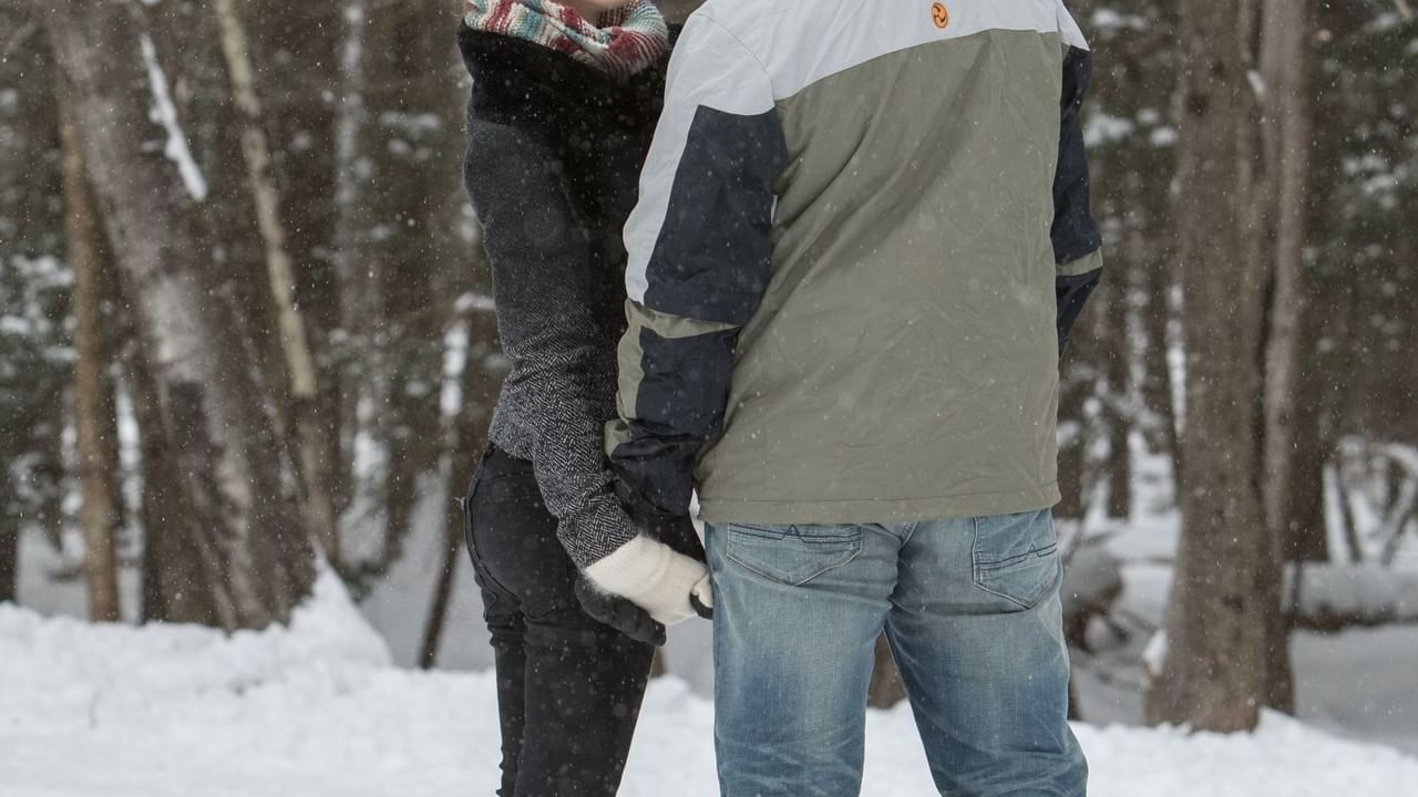 Couple holding hands while gazing at each other in the snowy forest near Cove Pocono Resorts